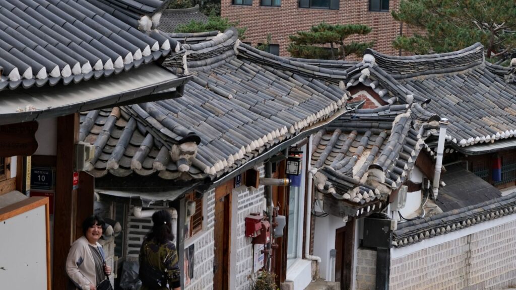 Traditionelle Hanok-Dächer im Bukchon Hanok Village mit der Skyline von Seoul dahinter
