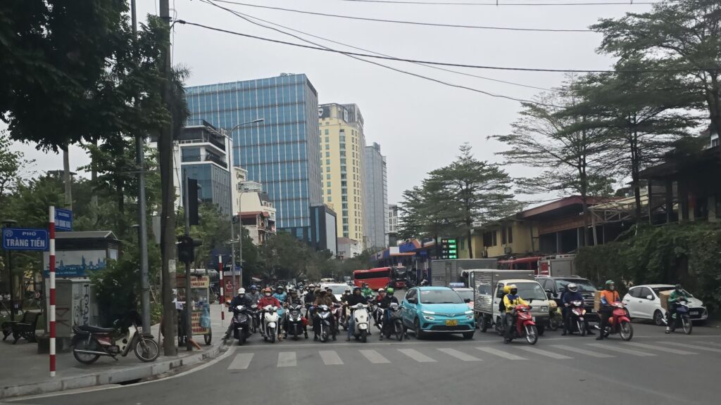 Mopedverkehr in der Altstadt von Hanoi an einer belebten Kreuzung im Dezember